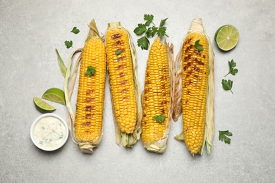 Photo of Delicious grilled corn cobs on light table, flat lay