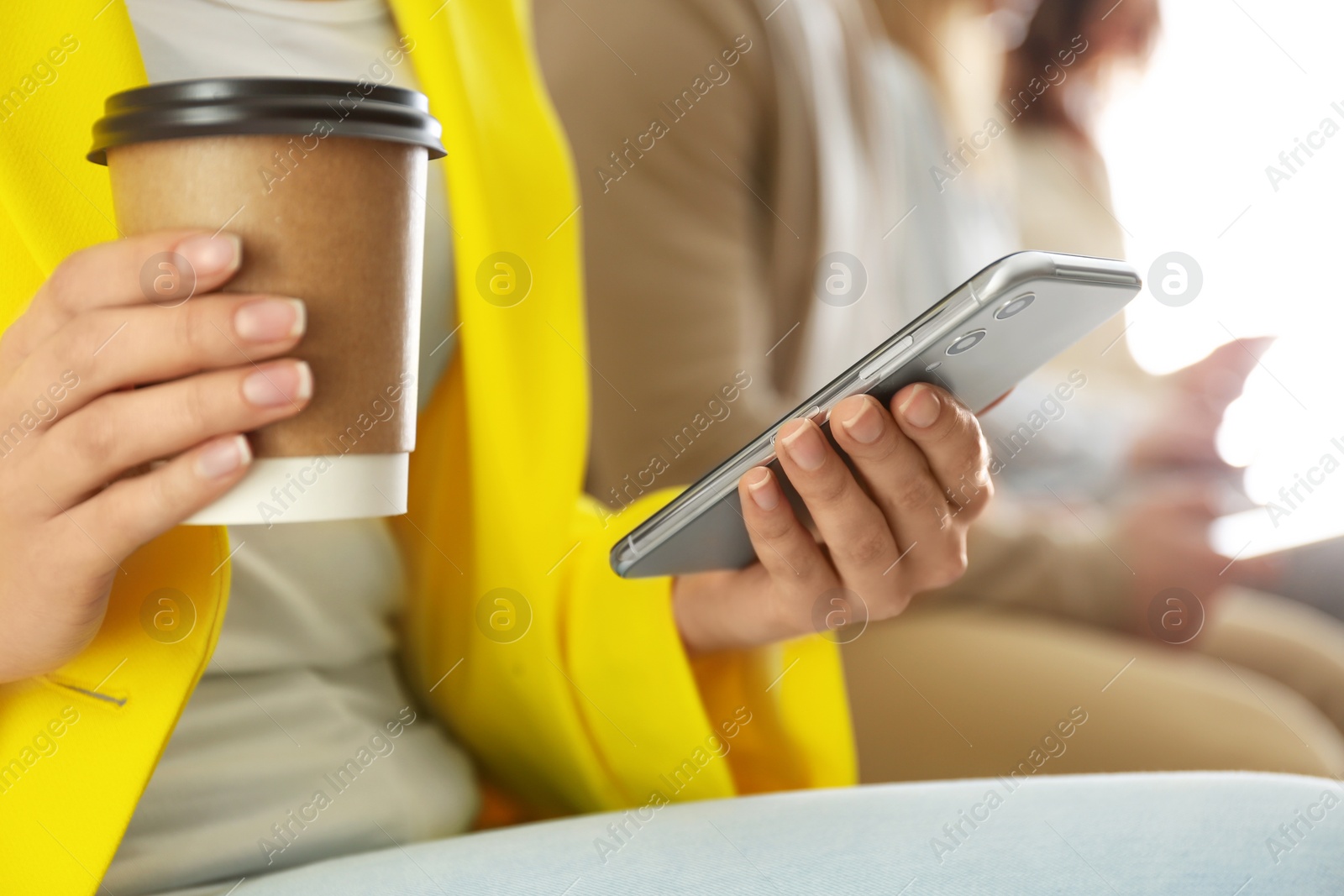 Photo of Woman with cup of coffee using smartphone, closeup