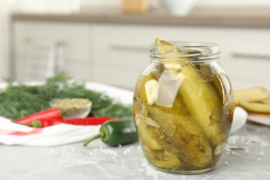 Photo of Jar with pickled cucumbers on grey table in kitchen