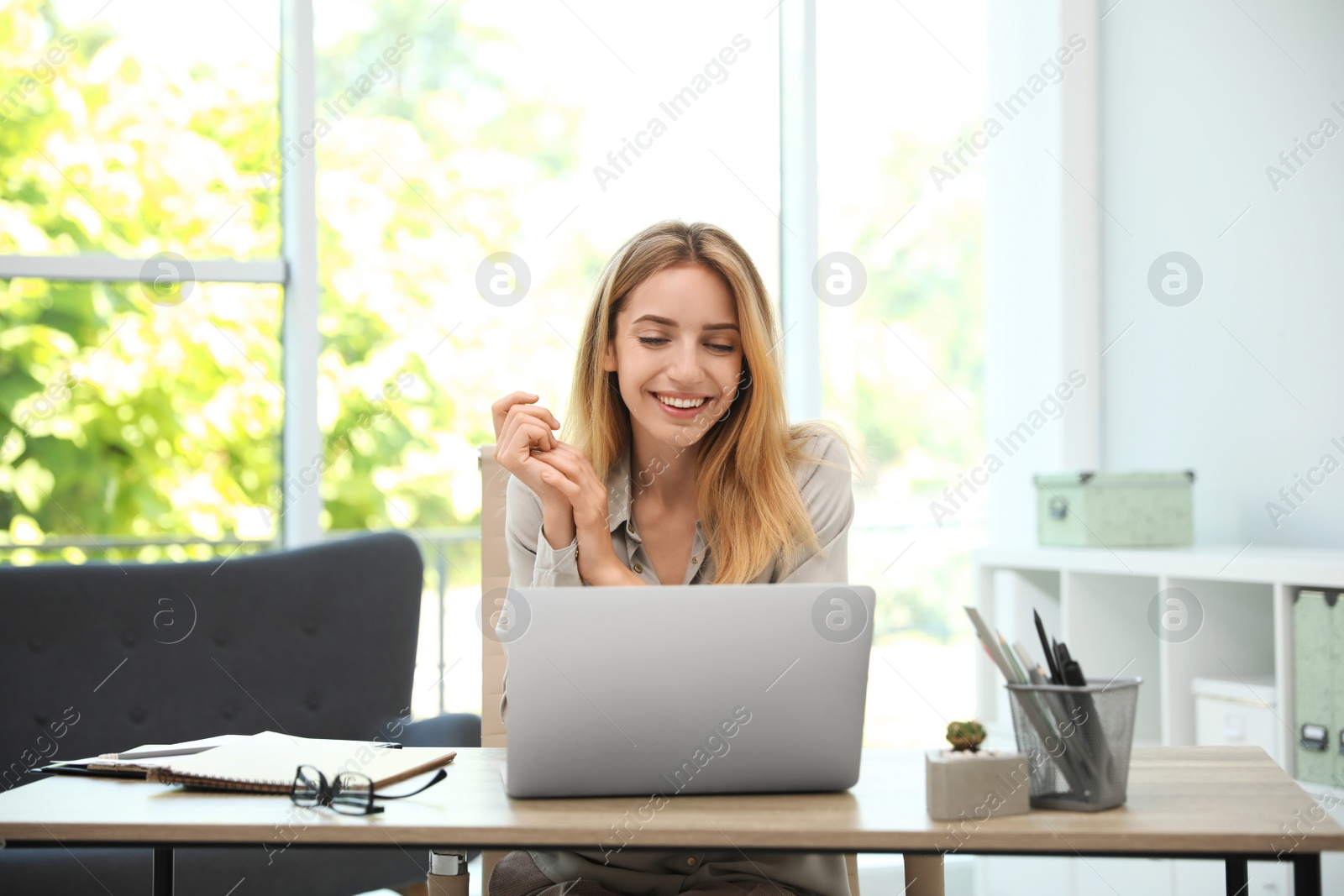 Photo of Pretty young woman working with laptop in office