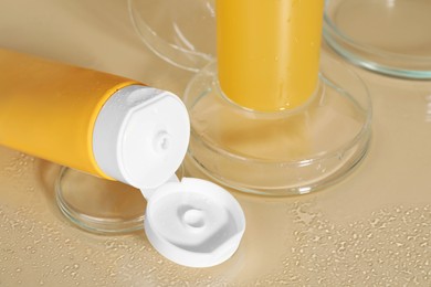 Wet face cleansing products and petri dishes on beige background, closeup