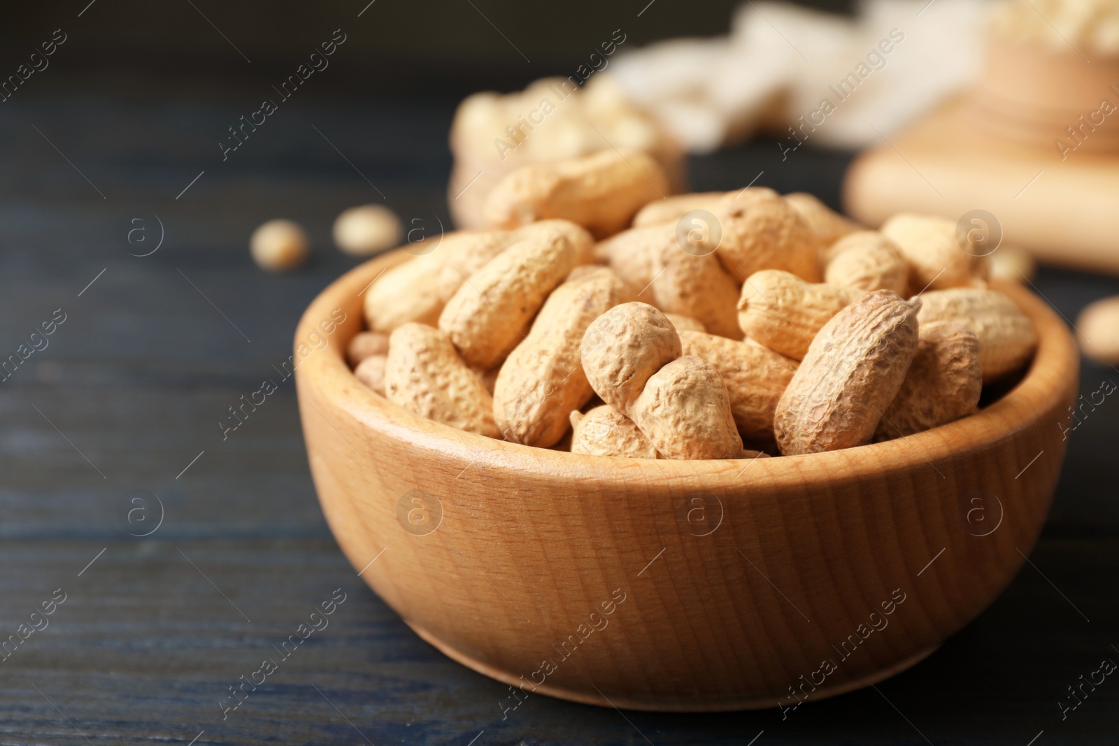 Photo of Bowl with peanuts in shell on table