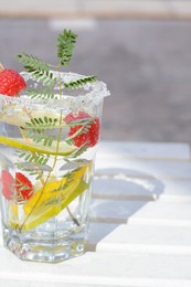 Photo of Delicious refreshing lemonade on white wooden table outdoors