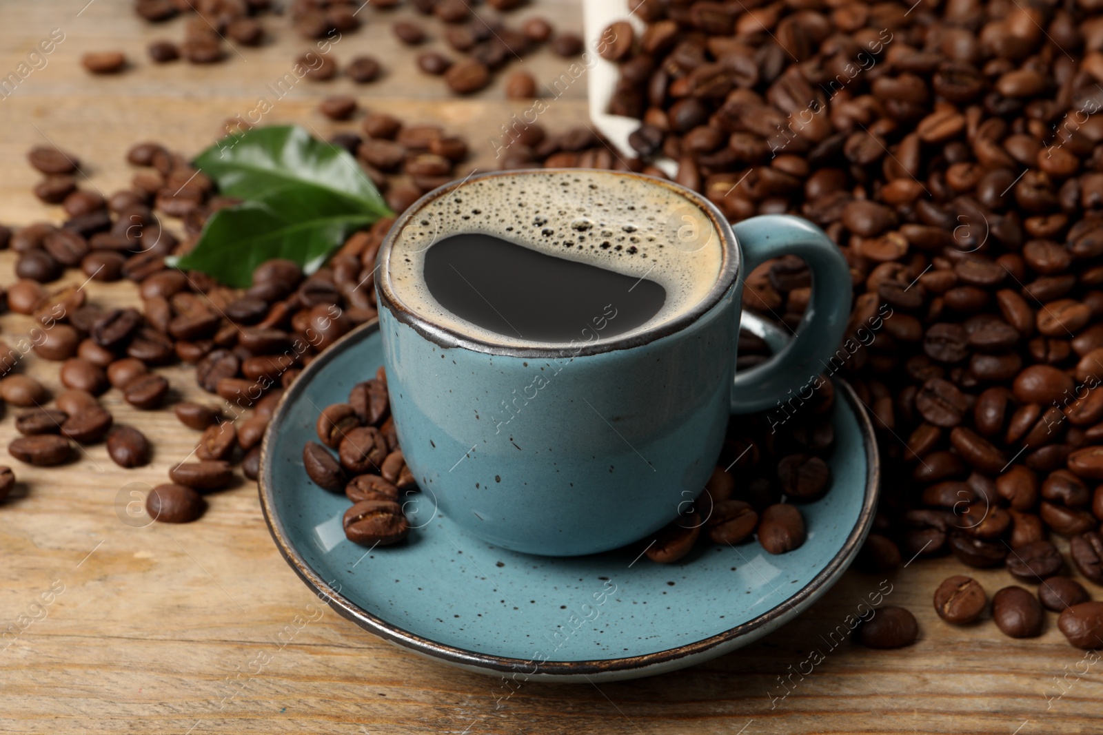 Photo of Cup of aromatic hot coffee and beans on wooden table