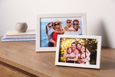 Photo of Frames with family photos on wooden table near white wall