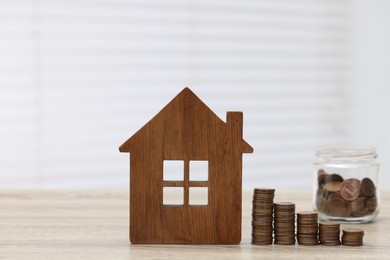 Photo of House model and stacked coins on wooden table