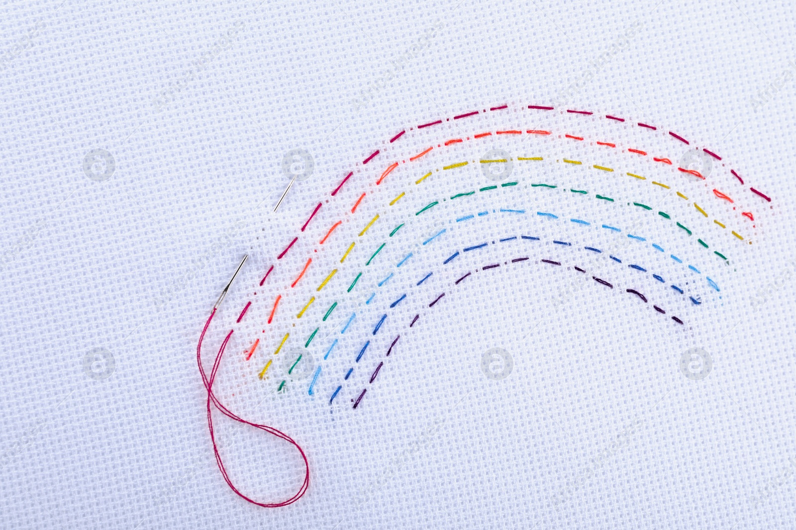 Photo of Canvas with embroidered rainbow and needle, top view