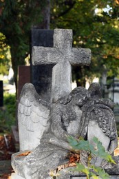 Photo of Beautiful statue of angel with cross at cemetery. Religious symbol
