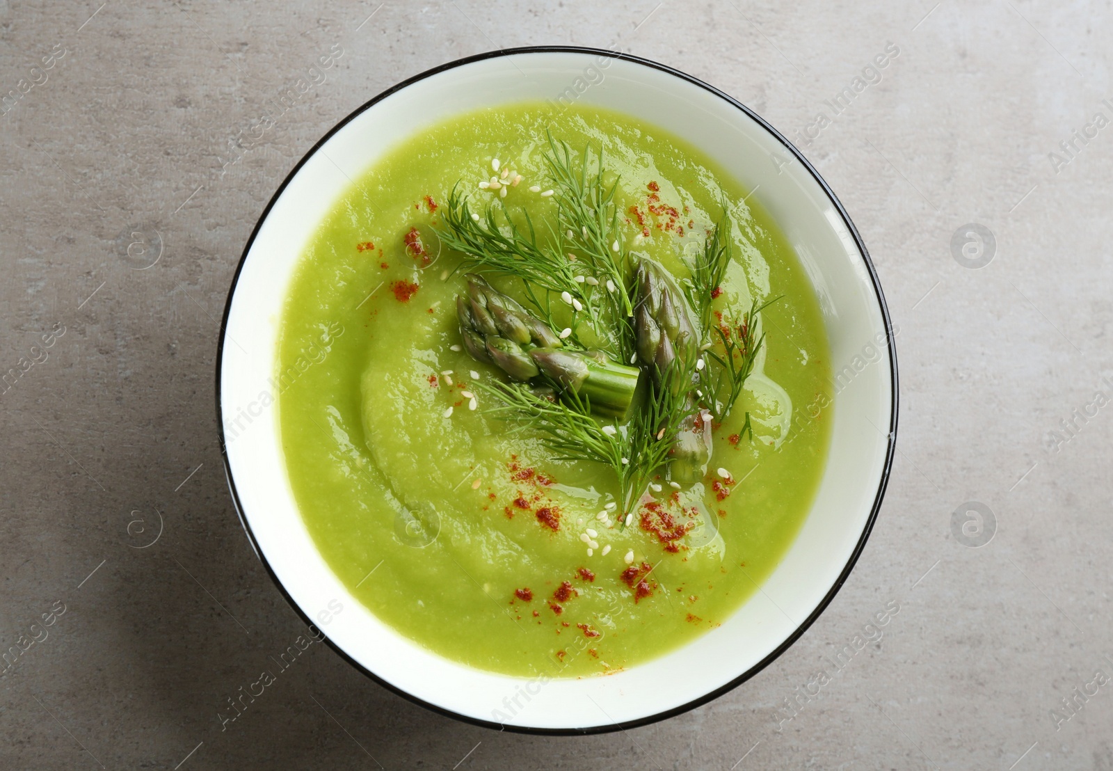 Photo of Delicious asparagus soup in bowl on grey table, top view