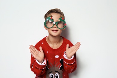Photo of Cute little boy in Christmas sweater with party glasses on white background