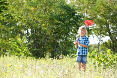Photo of Cute little boy with butterfly net outdoors, space for text. Child spending time in nature