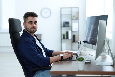 Photo of Young programmer working at desk in office