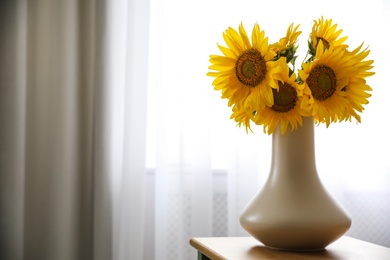 Photo of Bouquet of beautiful sunflowers on table indoors. Space for text