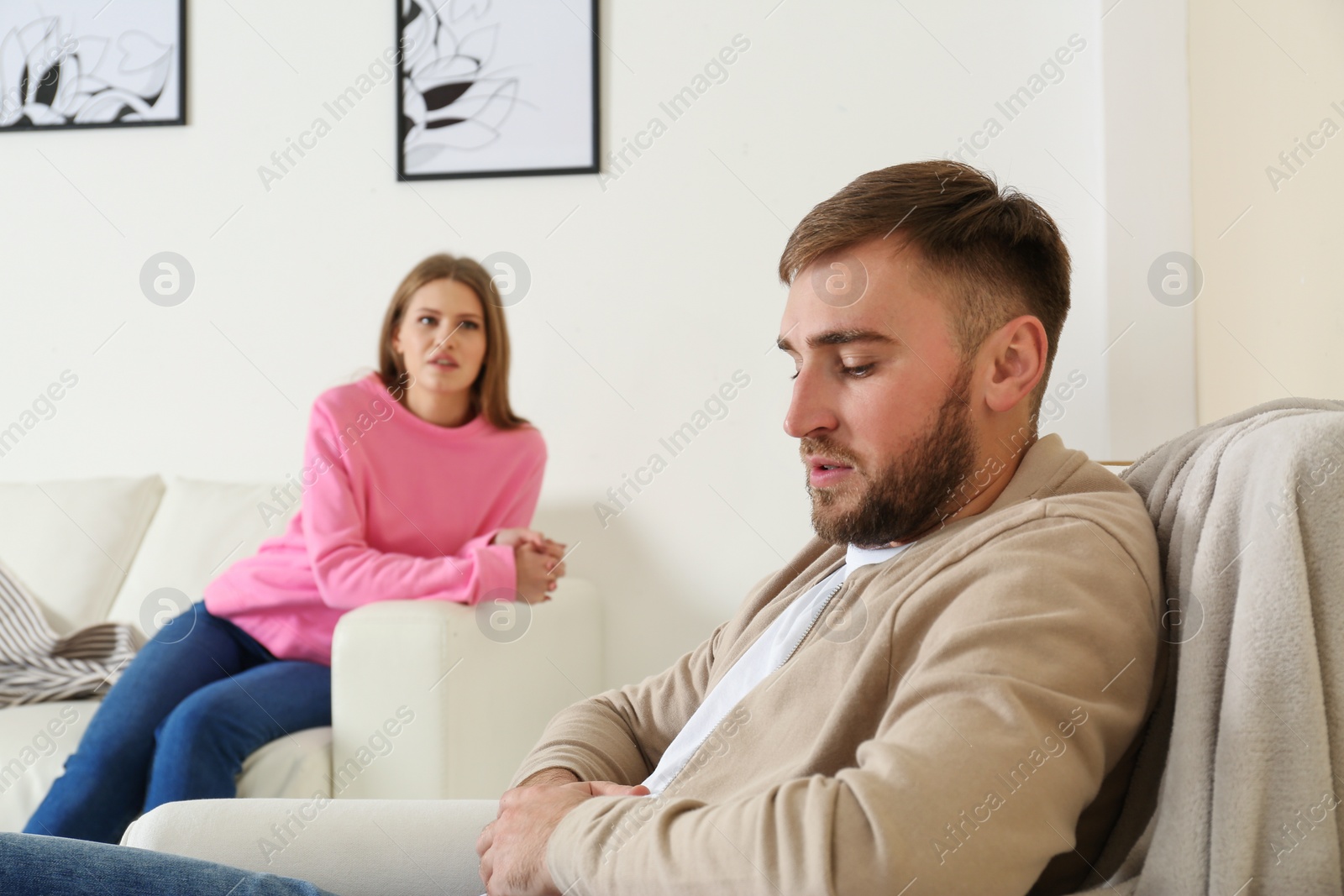 Photo of Young couple ignoring each other after argument in living room. Relationship problems