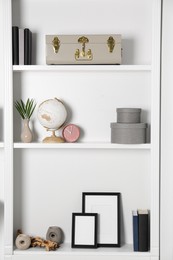 Photo of White shelves with globe, clock and different decor indoors. Interior design