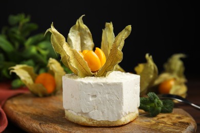 Photo of Delicious dessert decorated with physalis fruit on wooden board