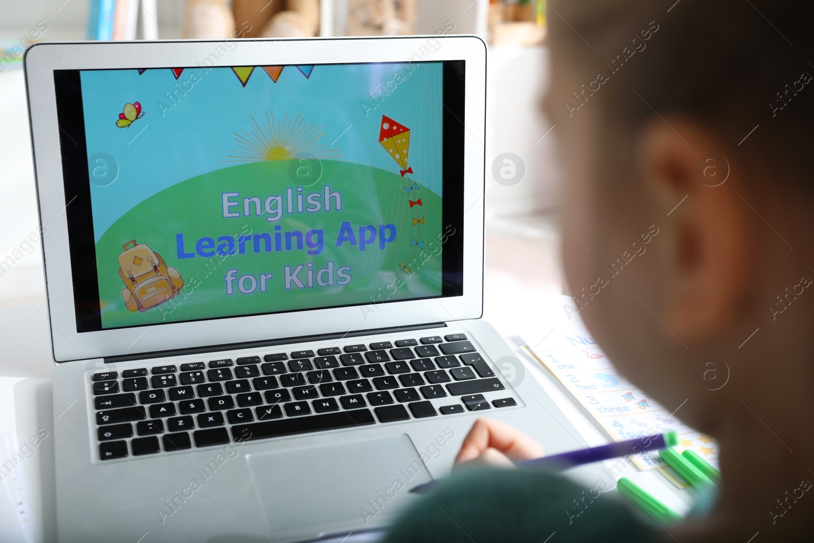 Photo of Little girl learning English indoors at online lesson, closeup