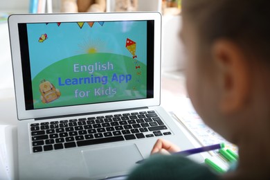 Photo of Little girl learning English indoors at online lesson, closeup