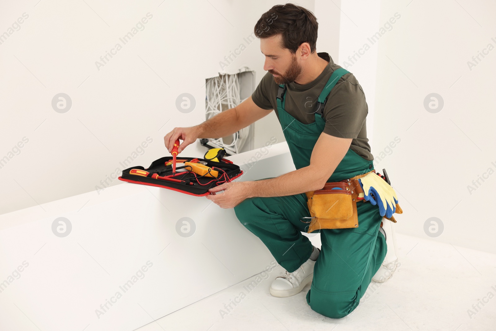 Photo of Electrician taking screwdriver from tool bag indoors