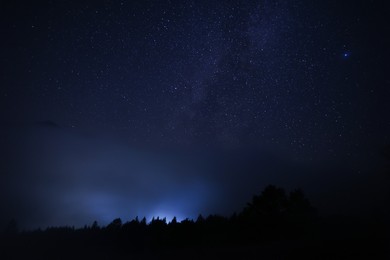 Photo of Beautiful view of starry sky over dark misty forest at night