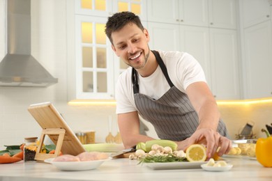 Man making dinner while watching online cooking course via tablet kitchen