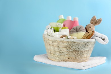 Photo of Basket with baby cosmetic products and accessories on light blue background. Space for text