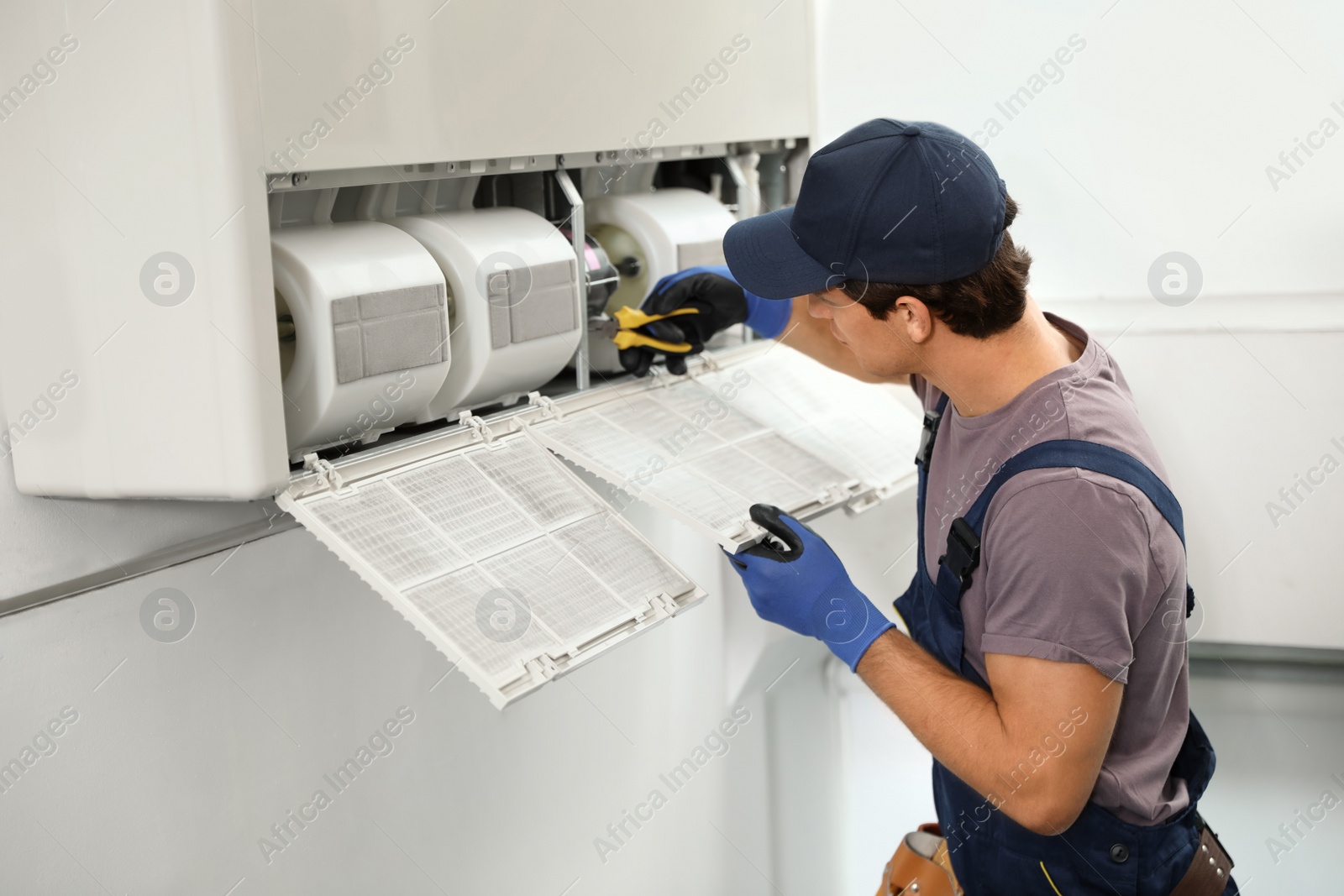 Photo of Male technician repairing air conditioner indoors