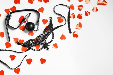 Composition with accessories for sexual role play and red hearts on white background, top view