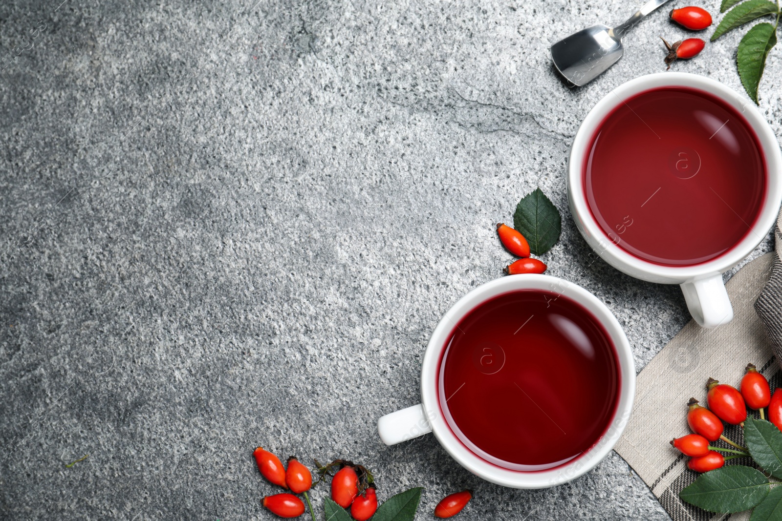 Photo of Fresh rose hip tea and berries on grey table, flat lay. Space for text