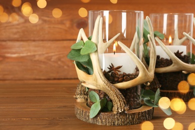 Photo of Stylish holders with burning candles, coffee beans and eucalyptus on wooden table. Space for text