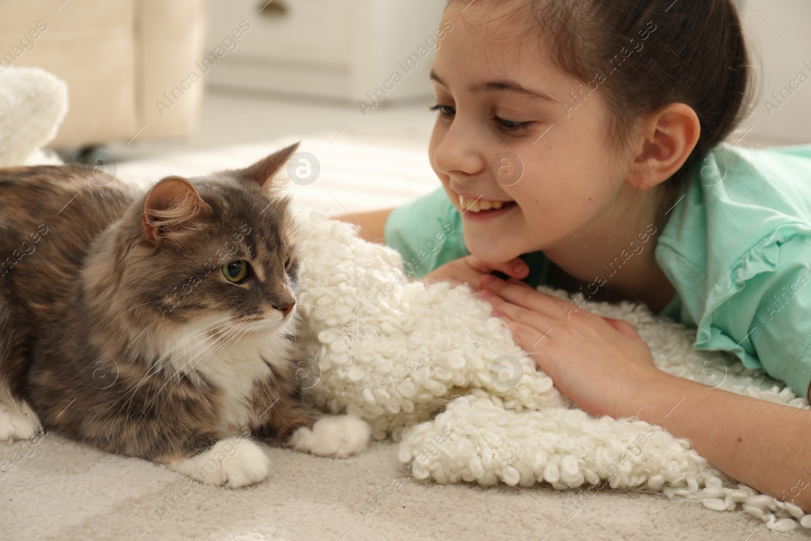 Photo of Cute little girl with cat lying on carpet at home. First pet