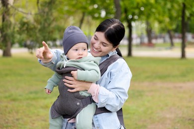 Mother holding her child in sling (baby carrier) in park