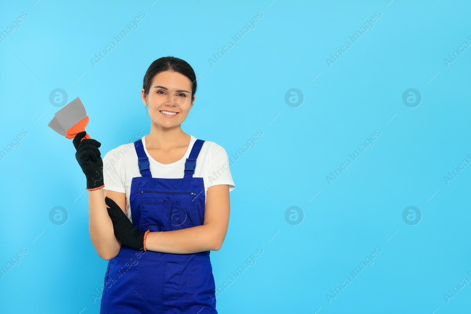 Photo of Professional worker with putty knives on light blue background, space for text