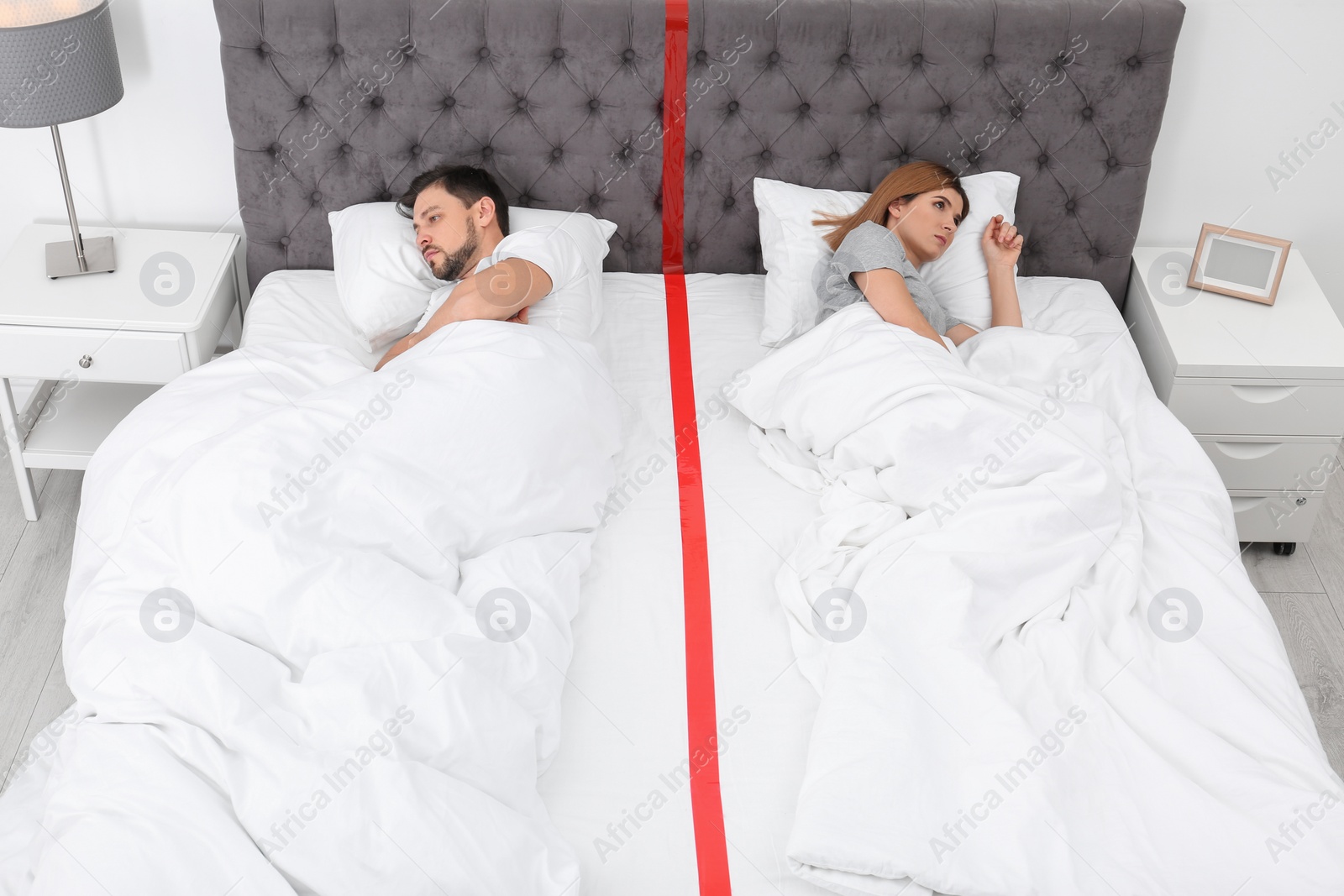 Photo of Upset couple with relationship problems lying separately in bed at home