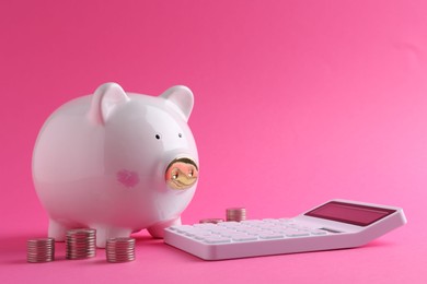 Financial savings. Piggy bank, coins and calculator on pink background