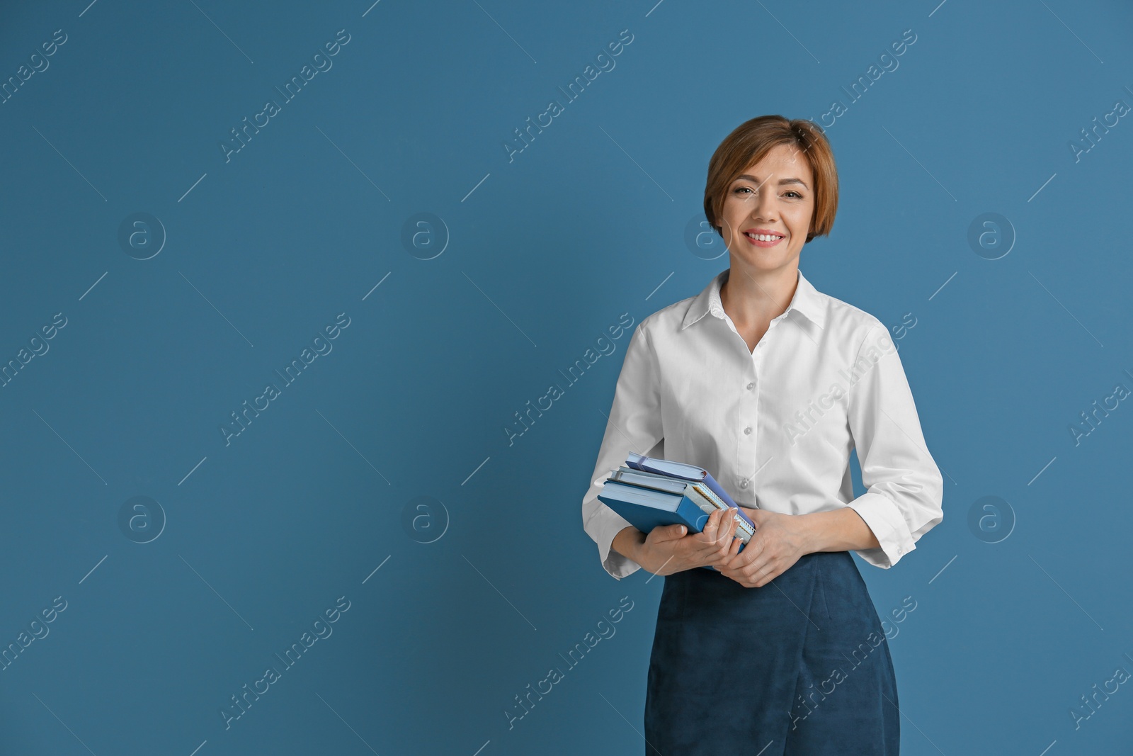 Photo of Portrait of female teacher with notebooks on color background