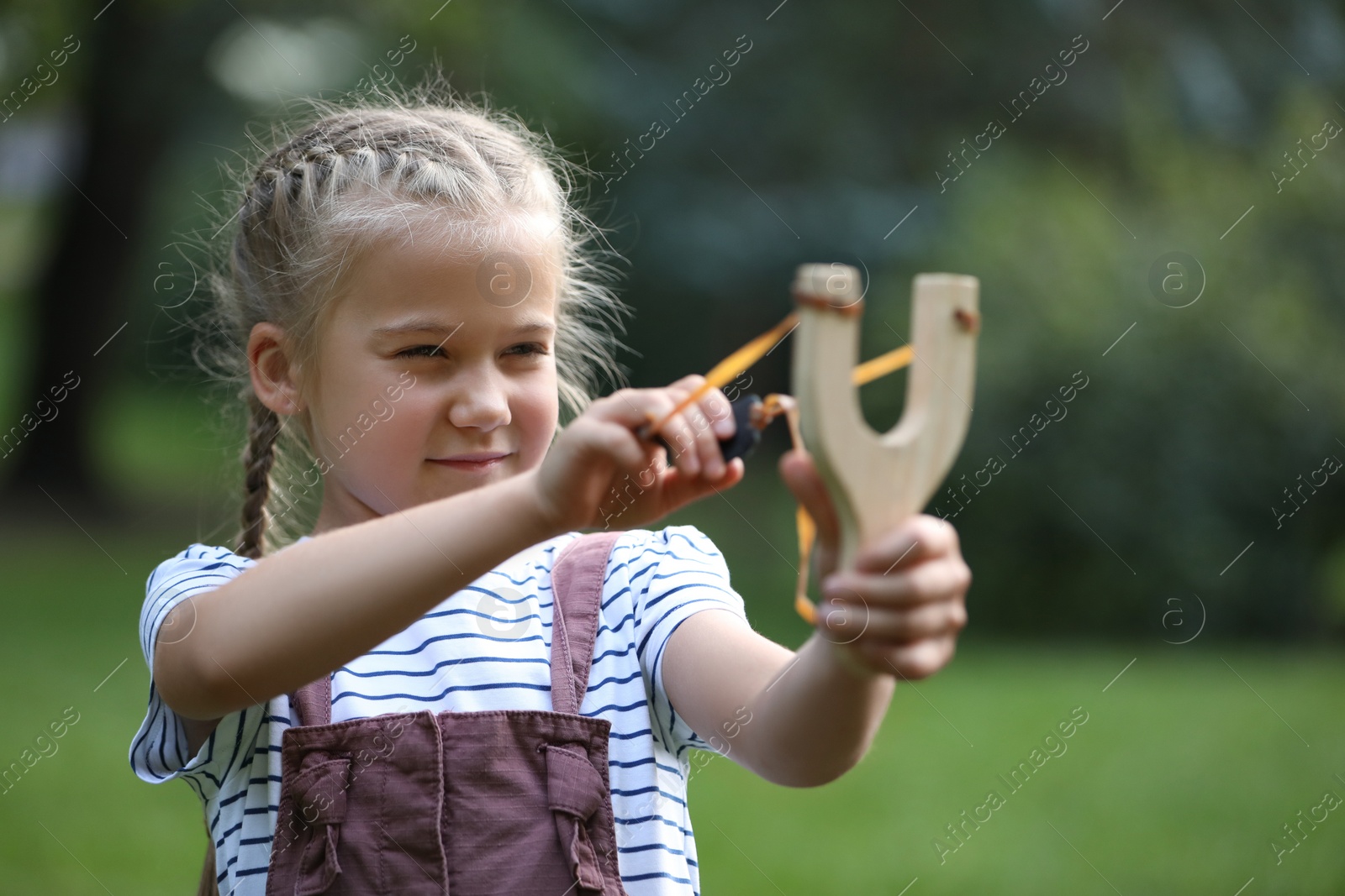 Photo of Little girl playing with slingshot in park