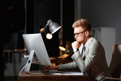 Photo of Concentrated young businessman working in office alone at night