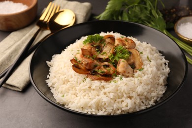 Photo of Delicious rice with parsley and mushrooms on grey table, closeup