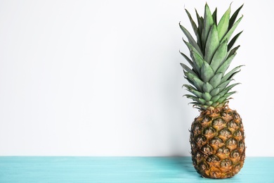 Photo of Fresh ripe juicy pineapple on light blue wooden table. Space for text