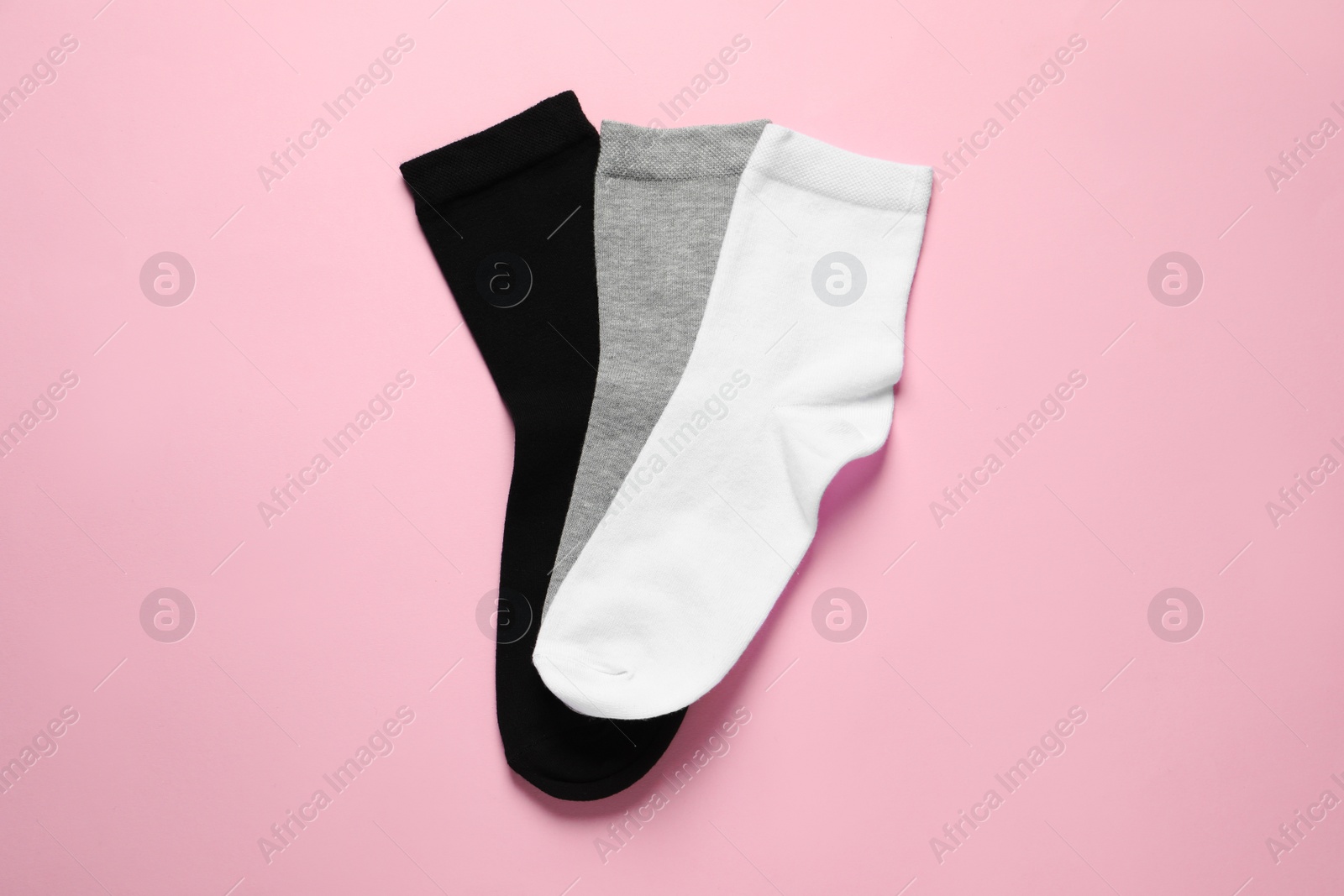 Photo of Different socks on pink background, flat lay