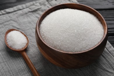 Photo of Granulated sugar in bowl and spoon on towel, closeup