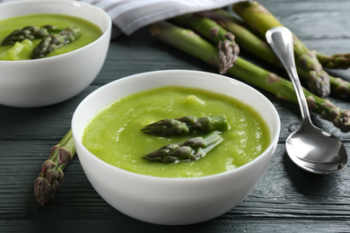 Delicious asparagus soup served on grey wooden table