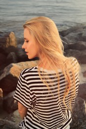 Beautiful young woman on rocky sea beach