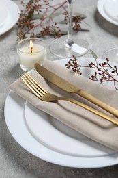 Photo of Stylish table setting with cutlery, burning candle and eucalyptus leaves