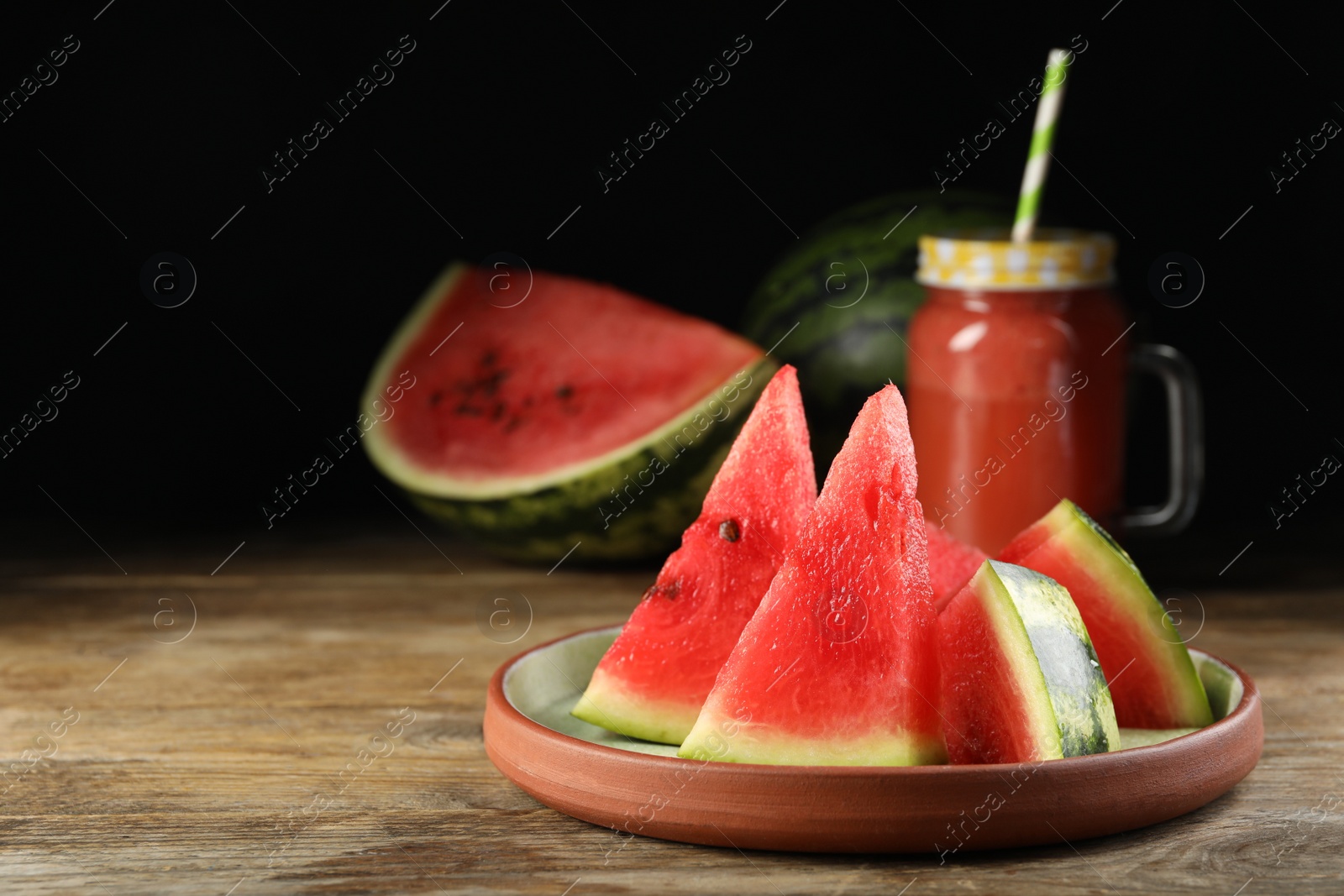 Photo of Plate with slices of juicy watermelon on wooden table, space for text