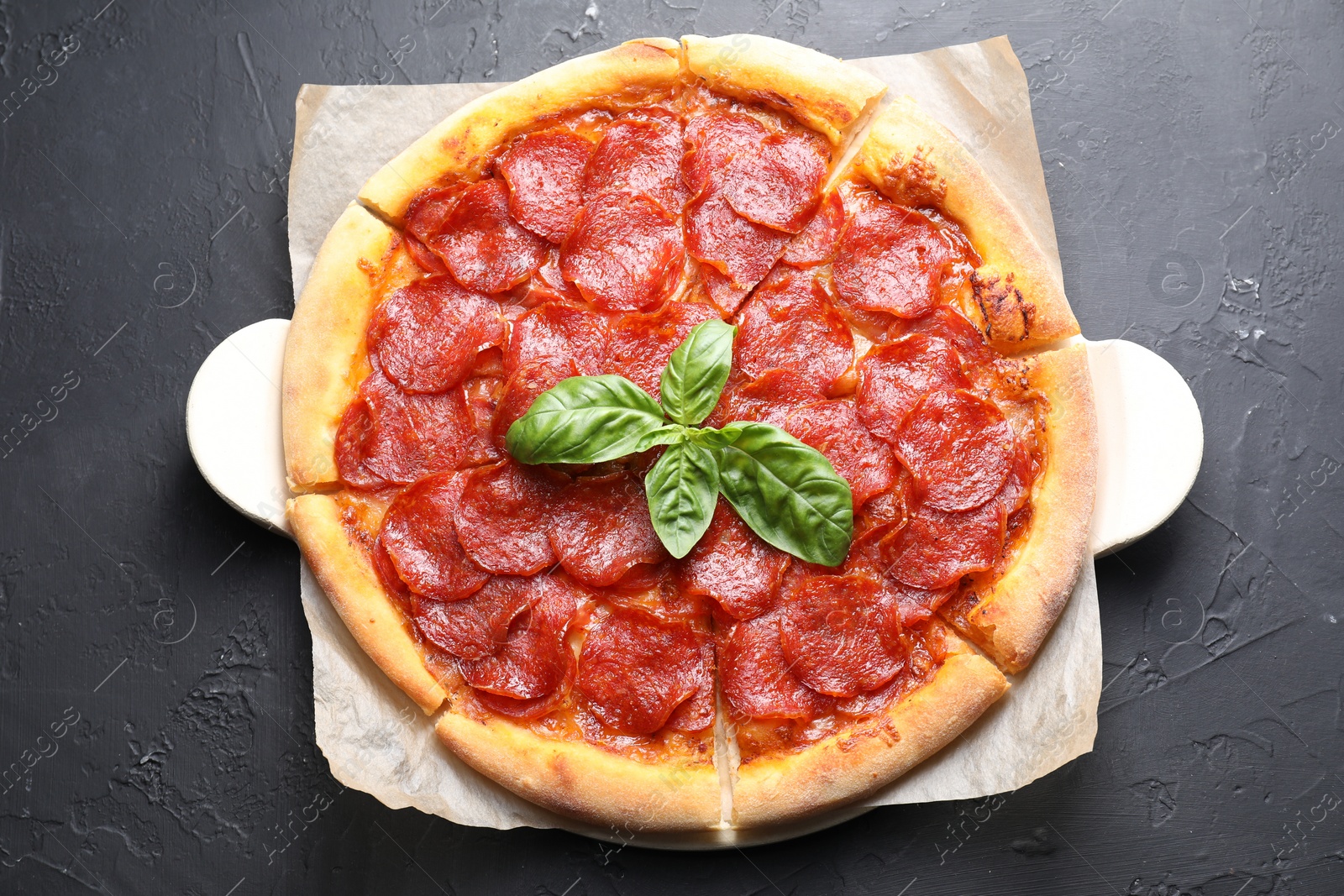 Photo of Tasty pepperoni pizza on black textured table, top view