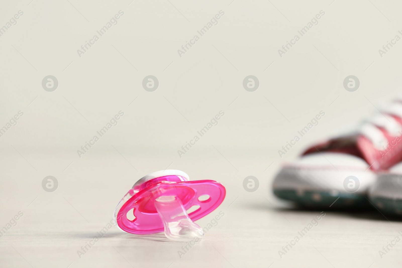 Photo of Baby pacifiers on beige table against blurred background, space for text