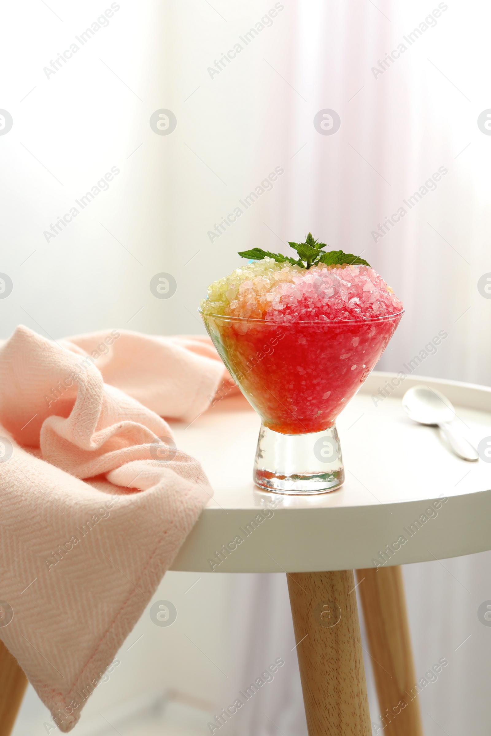 Photo of Shaving ice in glass dessert bowl on white table indoors