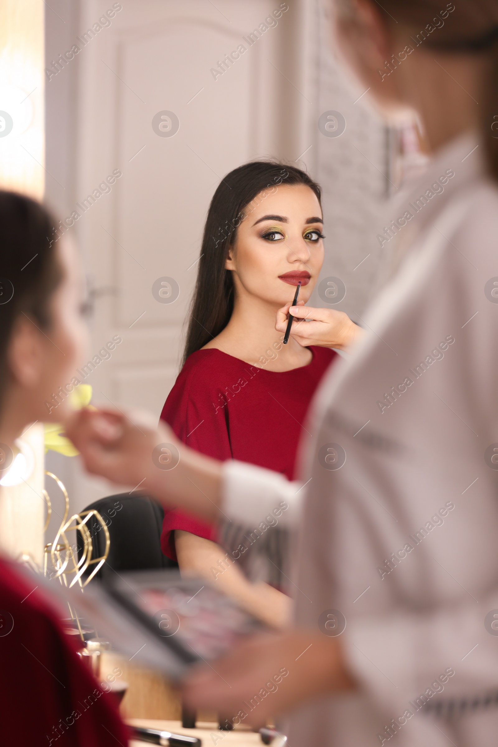 Photo of Professional visage artist applying makeup on woman's face in salon